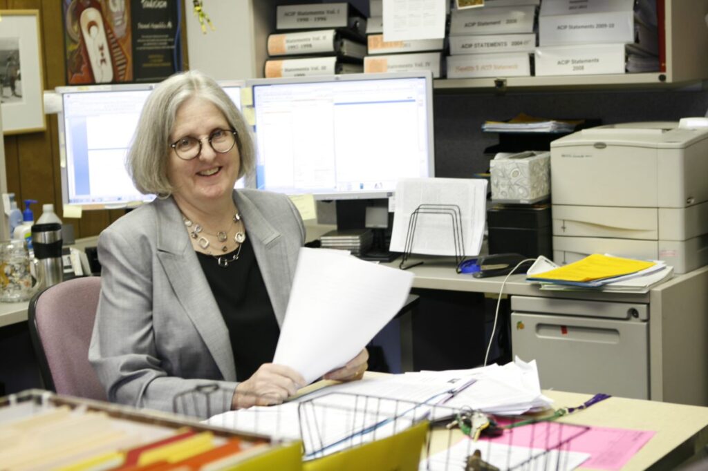 Deborah Wexler at her desk, smiling.